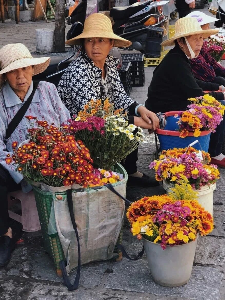 Yunnan Spring Markets — a flower seller surrounded by bright bouquets
