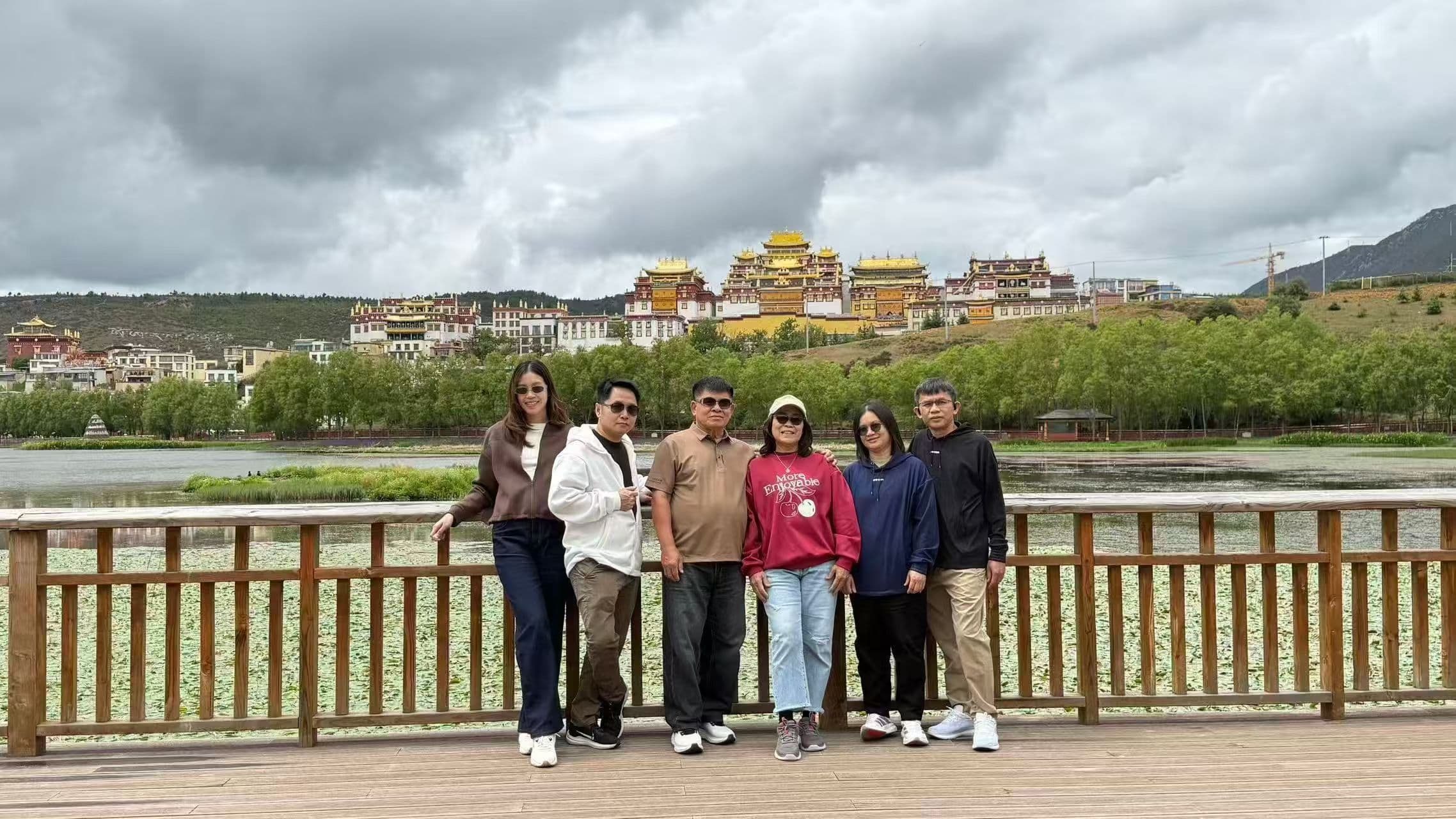 Travel group on a bridge beneath dramatic clouds in Yunnan