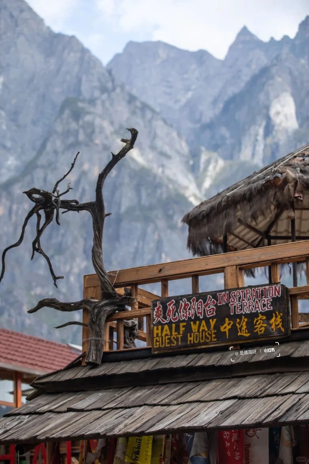 Tiger Leaping Gorge — a guesthouse sign beneath jagged peaks