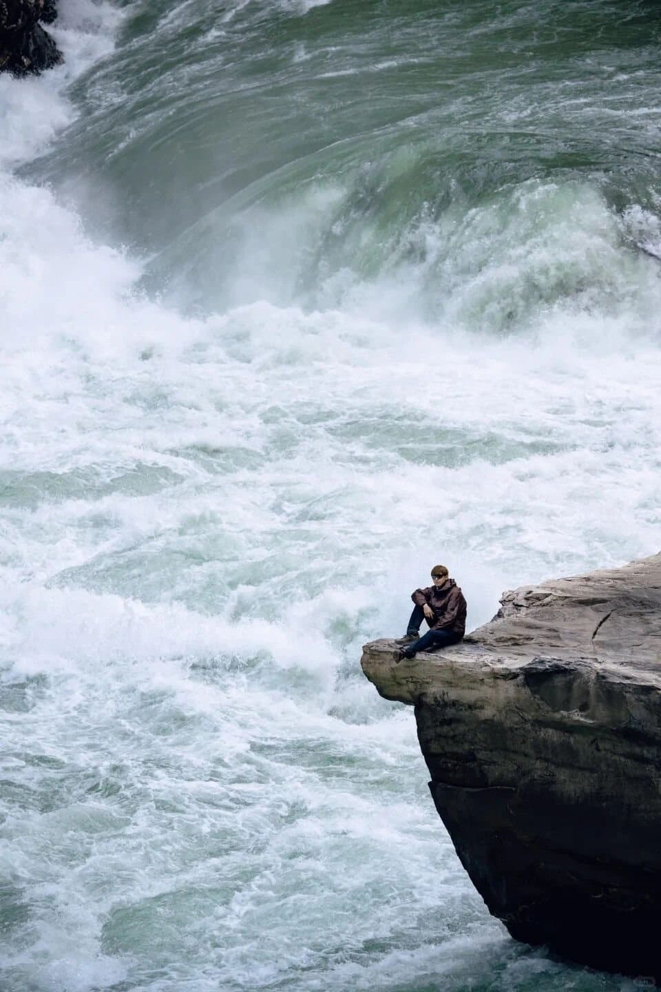 Tiger Leaping Gorge — a traveler standing beside the rushing river