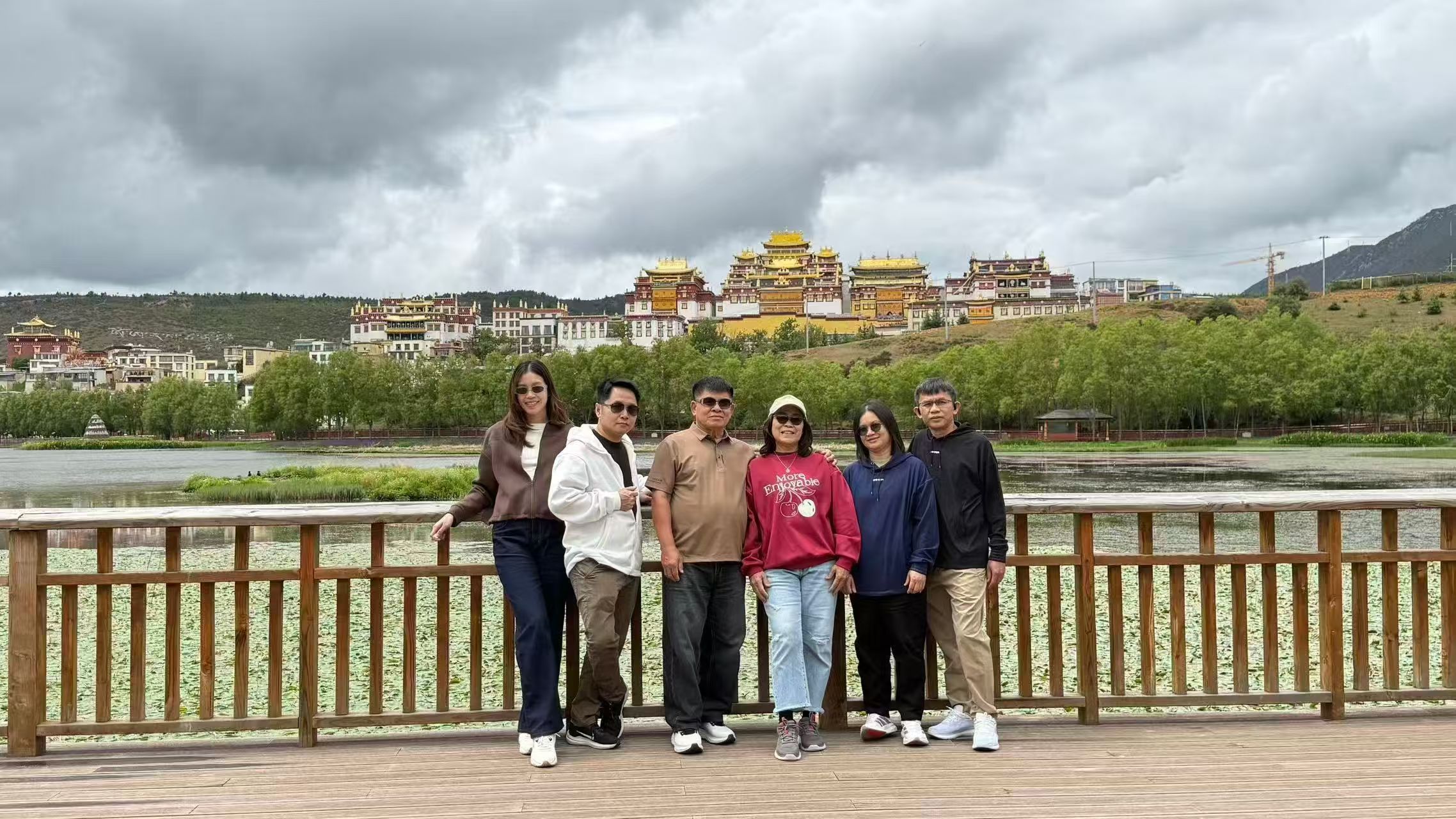 Travel group on a bridge beneath dramatic clouds in Yunnan